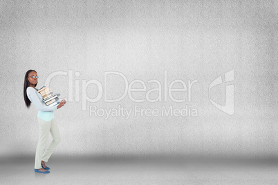 Composite image of side view of young woman carrying a pile of b