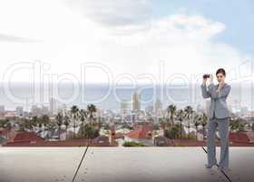 Composite image of businesswoman posing with binoculars