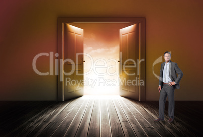 Composite image of smiling businessman with hand on hip