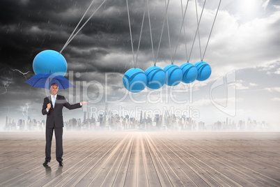 Composite image of peaceful businessman holding blue umbrella