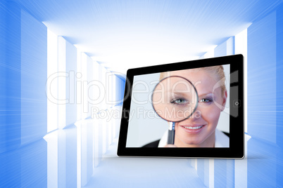 Composite image of businesswoman holding magnfying glass on tabl