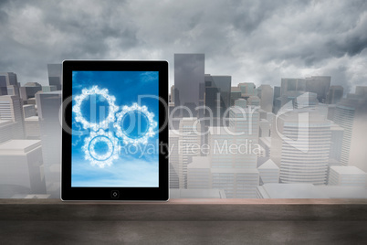 Composite image of cogs in clouds on tablet screen
