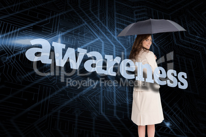 Businesswoman holding umbrella behind the word awareness