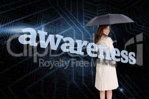 Businesswoman holding umbrella behind the word awareness