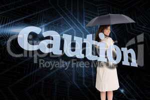 Businesswoman holding umbrella behind the word caution