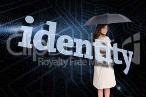 Businesswoman holding umbrella behind the word identity