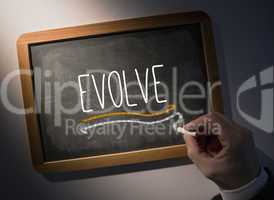 Hand writing Evolve on chalkboard