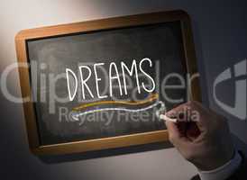 Hand writing Dreams on chalkboard