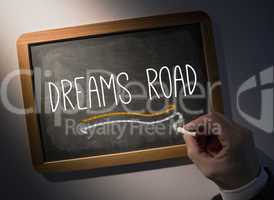 Hand writing Dreams road on chalkboard