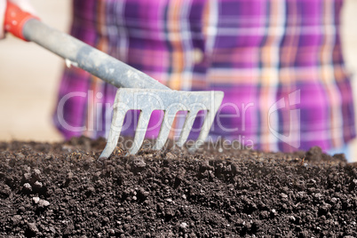 woman works with rake their humus soil