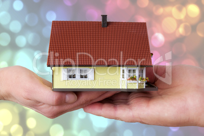 hands of woman and man holding model house