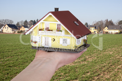 hand holding model house on the building site
