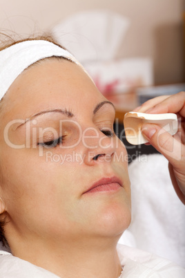 kosmetikerin trägt flüssiges make up auf