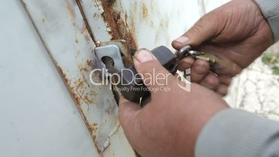 closeup of man opening barn lock with keys
