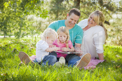 Young Family Enjoys Reading a Book in the Park