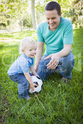 Young Boy and Dad Playing with Soccer Ball in Park