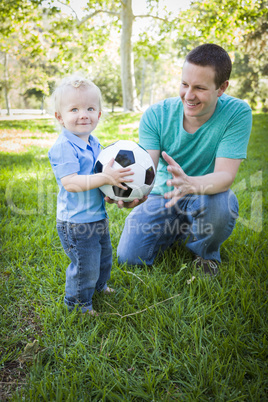 Young Boy and Dad Playing with Soccer Ball in Park