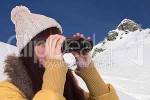 Junge Frau schaut in den Bergen durch ein Fernglas