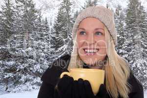 Junge blonde Frau trinkt draußen im Winter eine Tasse Tee