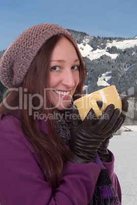 Junge Frau trinkt heiße Tasse Tee in den Bergen im Winter