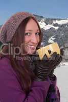 Junge Frau trinkt heiße Tasse Tee in den Bergen im Winter