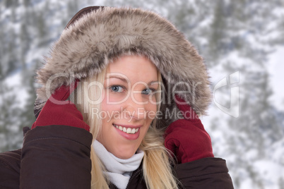 Junge Frau im Winter trägt Jacke mit Fellkragen gegen Kälte