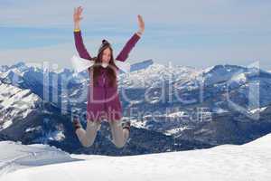 Junge Frau springt vor Glück und Freude in den Bergen