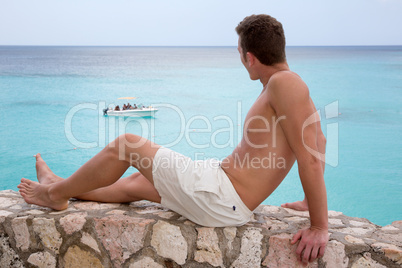 Junger Mann schaut im Urlaub aufs Meer