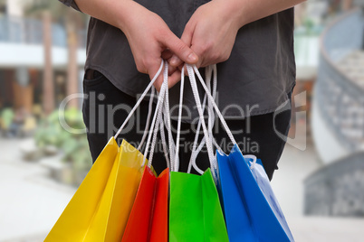 eine frau hält bunte einkaufstaschen in einer shopping mall in