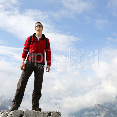 junger bergsteiger geniesst seinen erfolg auf dem berggipfel
