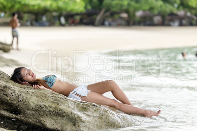woman lying on rocky beach