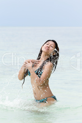 young woman in a bikini splashing in the sea