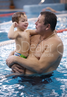 grandfather playing with his grandson in a swimming pool