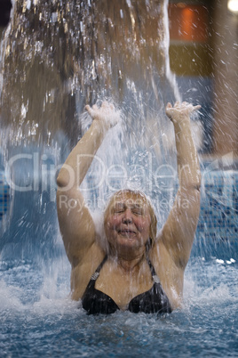 woman splashing in a pool under a jet of water