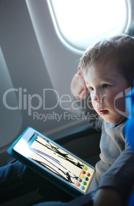 little boy drawing on a tablet in an airplane