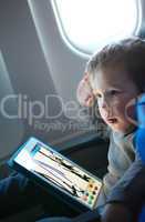 little boy drawing on a tablet in an airplane