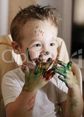 excited little boy playing with finger paints