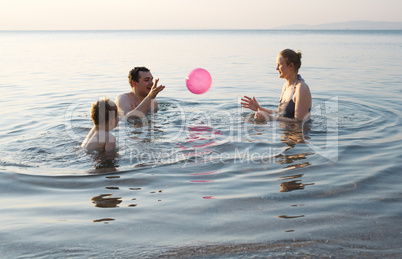 young family playing with ball at sunset