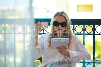 woman sitting reading a tablet -pc on a balcony