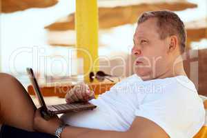man relaxing with a laptop at beach resort