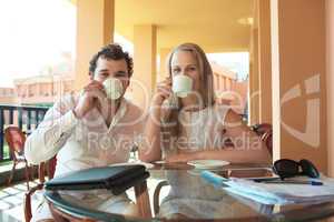 young couple drinking coffee on a balcony