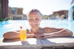 smiling young woman enjoying a drink in the pool