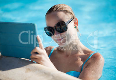 young woman using a tablet poolside