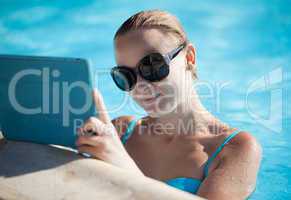 young woman using a tablet poolside