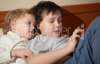 two young children playing with a tablet