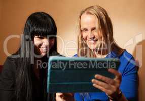 two young woman reading a tablet-pc