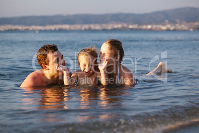 laughing little boy with his parents at the sea