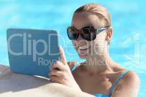 young woman in a pool using tablet computer