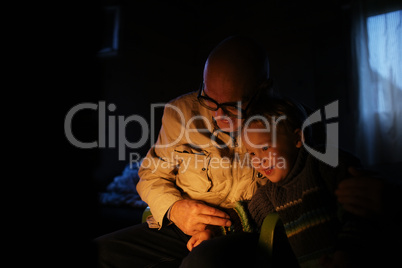 grandfather hugs his grandson near fireplace