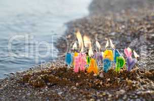 birthday candles burning on a seashore